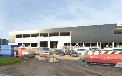 Bouwplaats met halfafgebouwd gebouw en voertuigen