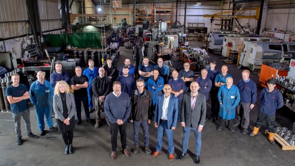 Groepsfoto in een fabriekshal met werknemers.